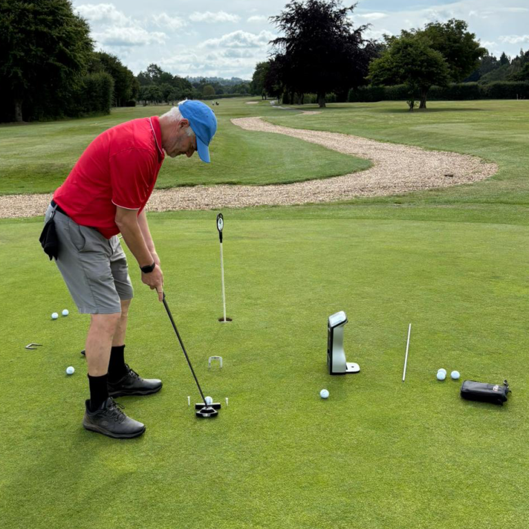  putting golf balls on a green, with a golf club and various training aids nearby. putting lessons at Cheshire  West Golf academy